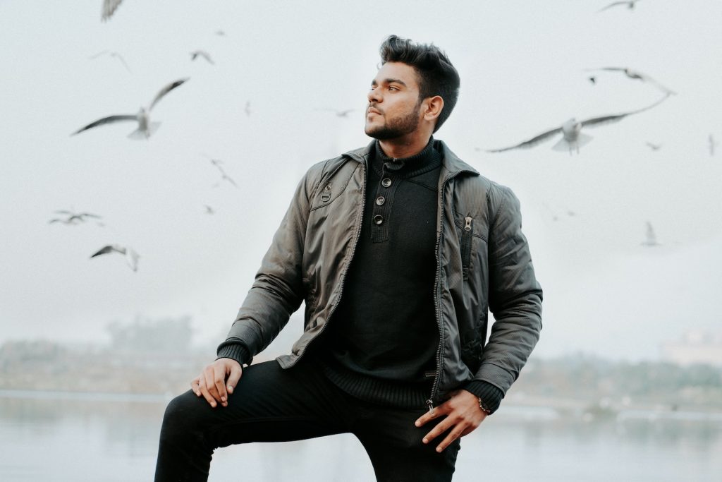 man in black leather jacket and black pants sitting on rock